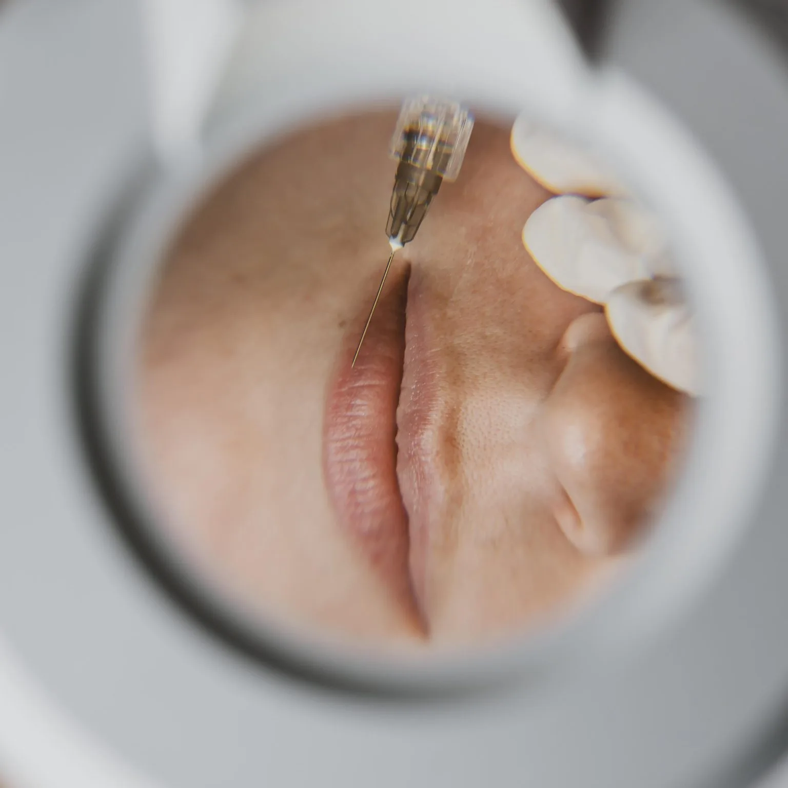 Lip tattoo macro through a ring light — needle to lip, no identity